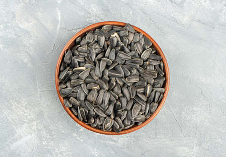 Large ceramic bowl with sunflower seeds on concrete background, top viewの写真素材