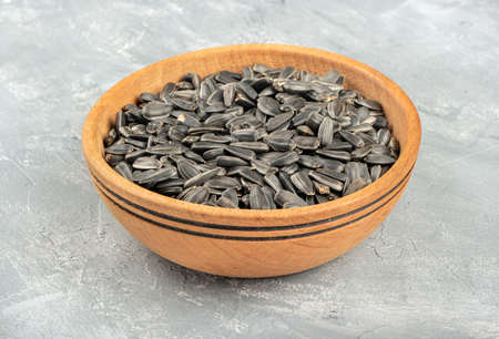 Large wooden bowl with sunflower seeds on concrete backgroundの写真素材