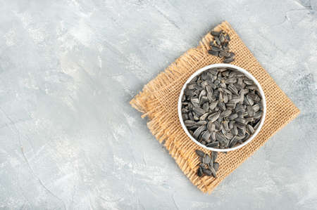 Ceramic bowl with sunflower seeds on burlap and concrete backgroundの写真素材