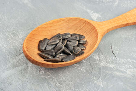 Sunflower seeds in a wooden spoon closeup on a light backgroundの写真素材