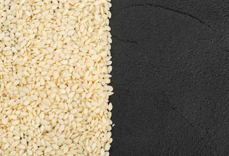 Scattered sesame seeds on a dark concrete background, top viewの写真素材