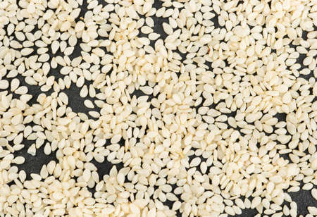 Scattered sesame seeds on a dark concrete background, top viewの写真素材