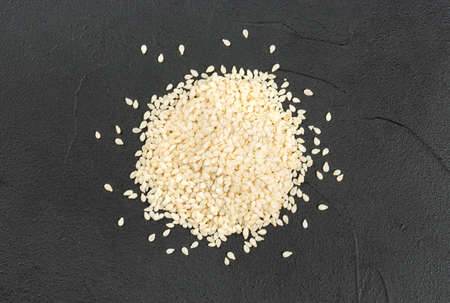 Pile of white sesame seeds on a dark concrete background, top viewの写真素材