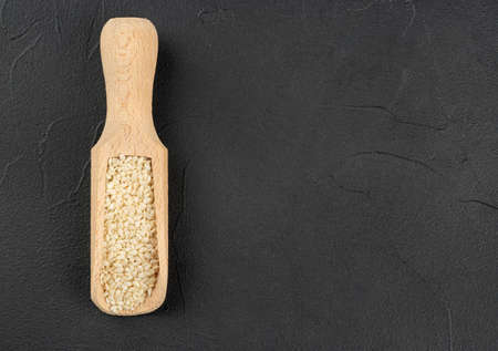 Sesame seeds in a wooden scoop on a concrete background, top viewの写真素材
