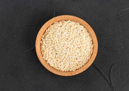 Sesame seeds in a wooden bowl on a dark background, top viewの写真素材