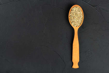 Dry fennel in a wooden spoon on an empty concrete background, top viewの写真素材