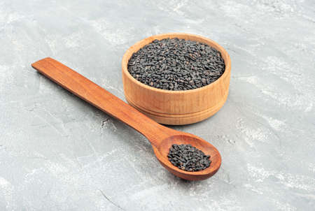 Black sesame seeds in the spoon and the bowl on a concrete backgroundの写真素材
