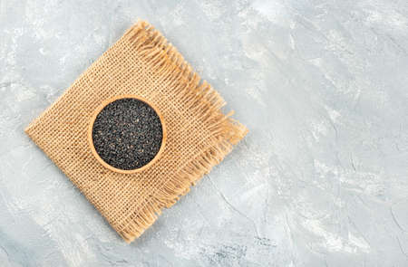 Black sesame in wooden bowl on burlap and concrete backgroundの写真素材