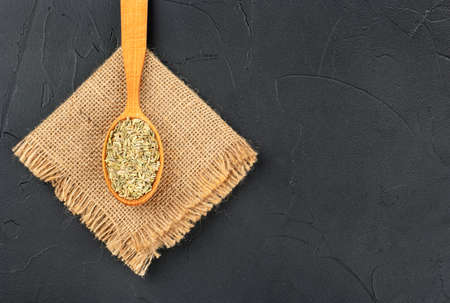 Dry fennel in spoon on burlap and empty dark backgroundの写真素材