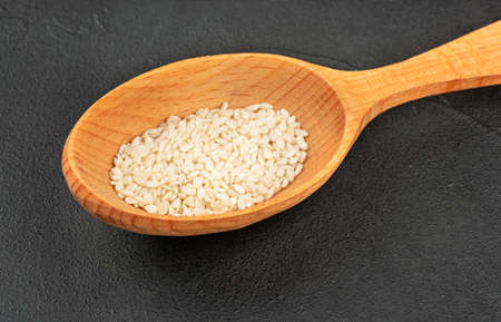 Sesame in a wooden spoon close up on a dark backgroundの写真素材