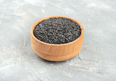 Black sesame seeds in a wooden bowl on a light backgroundの写真素材