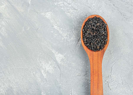 Small spoon with black sesame seeds on a light concrete background, top viewの写真素材