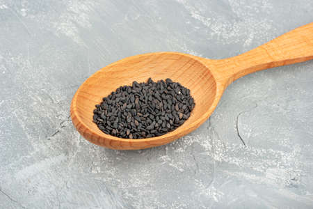 Black sesame in wooden spoon closeup on concrete backgroundの写真素材
