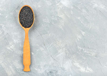 Black sesame in a wooden spoon on an empty light backgroundの写真素材