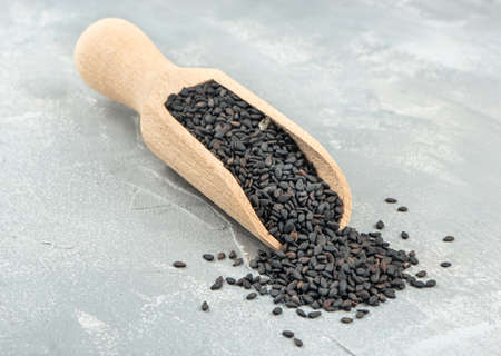 Black sesame in a wooden scoop on a light concrete backgroundの写真素材