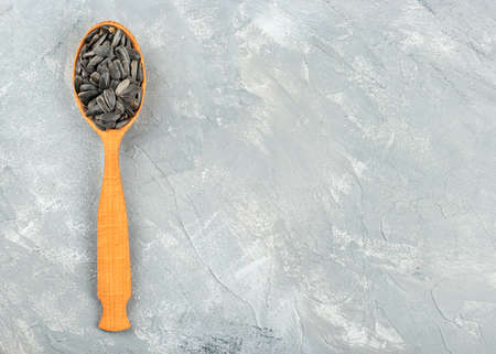 Sunflower seeds in a wooden spoon on an empty concrete backgroundの写真素材