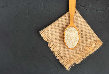 Sesame seeds in wooden spoon on burlap and dark backgroundの写真素材