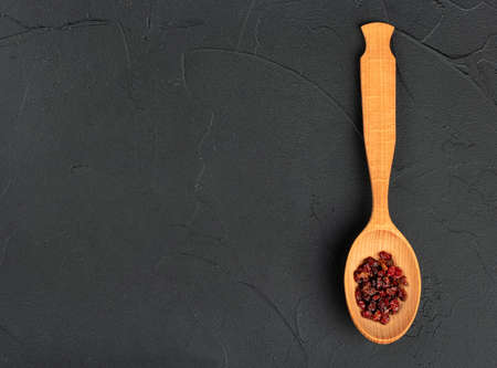 Dry barberry in a wooden spoon on an empty concrete backgroundの写真素材