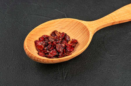 Dry barberry in a wooden spoon close up on a concrete backgroundの写真素材
