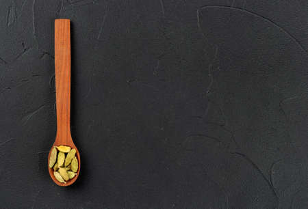 Small spoon with cardamom on empty dark background, top viewの写真素材