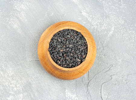 Black sesame in a wooden container on a light background, top viewの写真素材