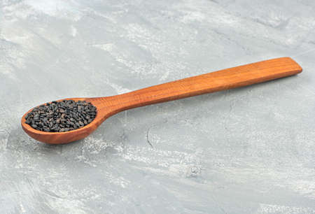Small spoon with black sesame seeds on a light concrete backgroundの写真素材