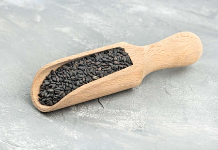 Black sesame in a wooden scoop on a light concrete backgroundの写真素材