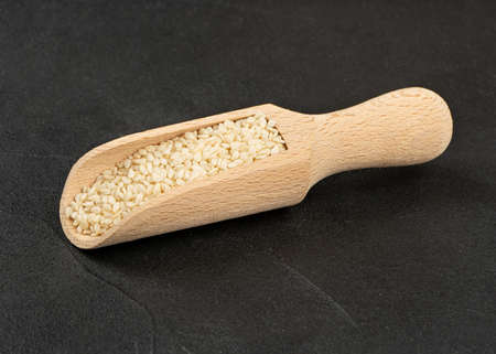 Sesame seeds in a wooden scoop on a concrete backgroundの写真素材