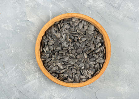 Large wooden bowl with sunflower seeds on concrete background, top viewの写真素材