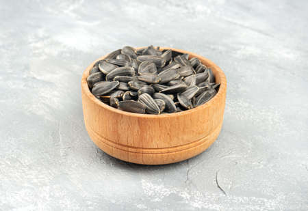 Sunflower seeds in a wooden bowl on a light concrete backgroundの写真素材
