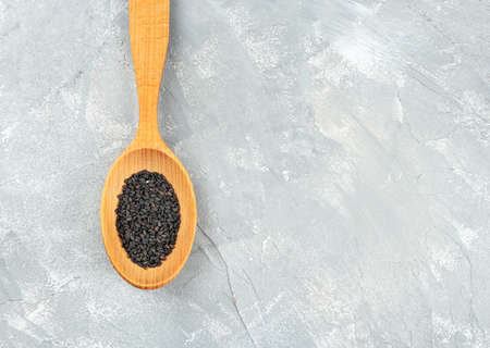 Black sesame in a wooden spoon on an empty light backgroundの写真素材