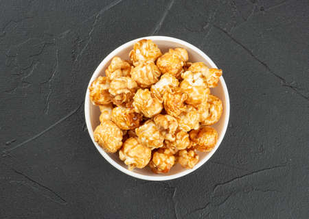 Caramel popcorn in bowl on dark background, top viewの写真素材