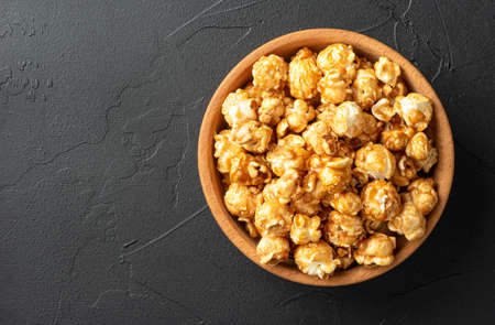 Caramel popcorn in wooden bowl on dark backgroundの写真素材