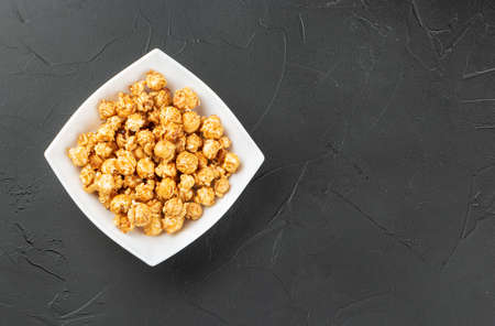 Caramel popcorn in ceramic bowl on dark backgroundの写真素材