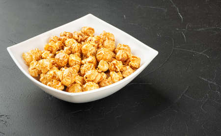 Caramel popcorn in ceramic bowl on concrete backgroundの写真素材