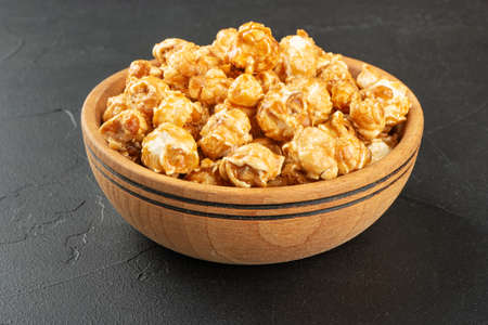 Wooden bowl with popcorn in caramel on concrete backgroundの写真素材