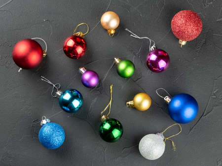Scattered multicolored Christmas balls on a dark background, top viewの写真素材