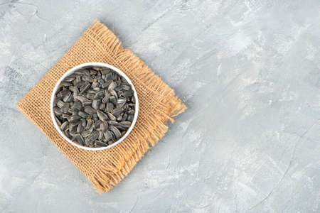Ceramic bowl with sunflower seeds on burlap and concrete backgroundの写真素材