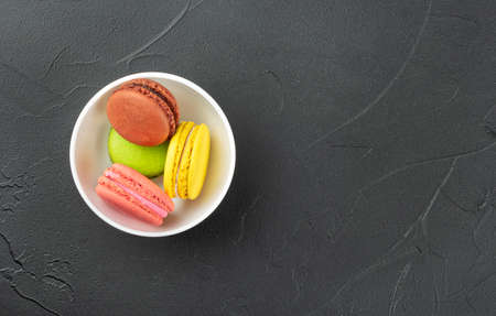 Multicolored macaroons in a white bowl on an empty concrete backgroundの写真素材