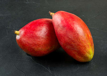 Two red delicious mango fruits on a concrete backgroundの写真素材