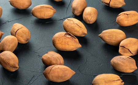 Scattered dry pecans in shell on dark concrete backgroundの写真素材