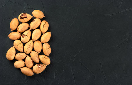Scattered pecans in shell close up on a dark background, top viewの写真素材