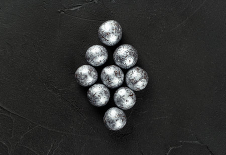 Silver candies hazelnuts in chocolate in the form of a rhombus on a dark concrete background top viewの写真素材