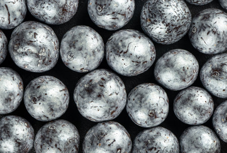Silver candies hazelnuts in chocolate scattered on a concrete dark background, close-up.