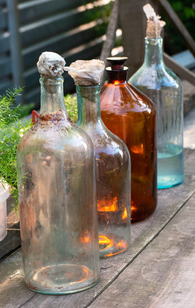 Several old and dirty glass bottles on a wooden table outside in the village.