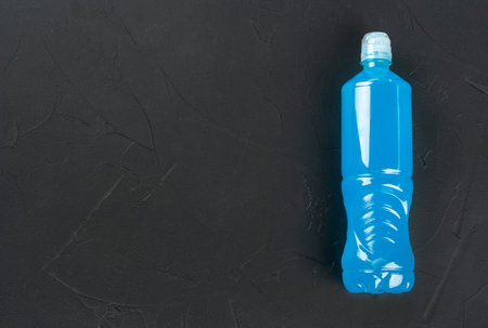 Blue isotonic drink for sports in a plastic bottle on an empty dark concrete background. copyspace. With vitamins and minerals for an active lifestyle.の写真素材