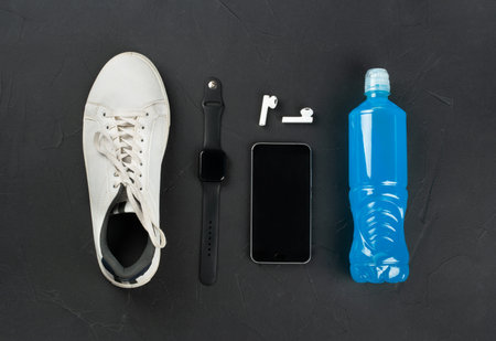 The concept of fitness and jogging. Background with a white sneaker, wireless headphones, a phone and a bottle of isotonic.の写真素材