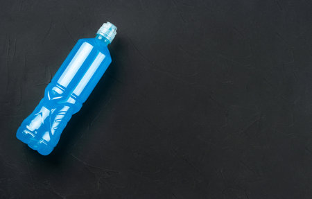 Plastic bottle with blue isotonic drinks for sports on a dark concrete background, copy space.の写真素材