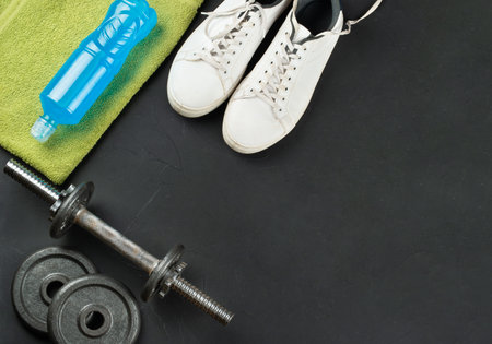 Isotonic drink bottle, dumbbells, towel and sneakers on a dark background. copy space. Running concept.の写真素材