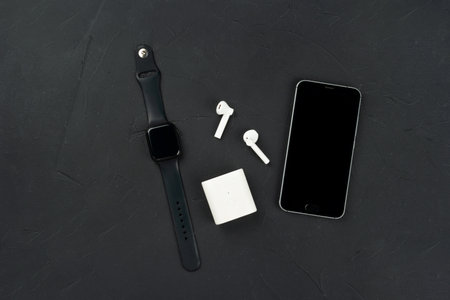 Fashion gadgets, mobile phone, smart watch and wireless headphones on a dark concrete background,...